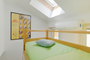 A bedroom with a bunk bed, a skylight, a poster on the wall, and an air conditioning unit.