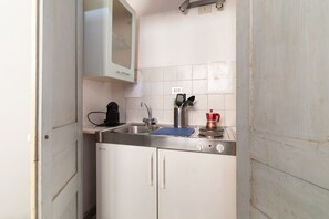 A compact kitchen with a stainless steel sink, a kettle, and a coffee maker.