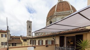 A rooftop terrace with outdoor seating, a view of the Florence Cathedral, and a bell tower. - Pallottole Duomo Apartments (Florence)