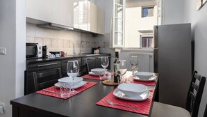 A modern kitchen with a dining area set for a meal. - Pallottole Duomo Apartments (Florence)