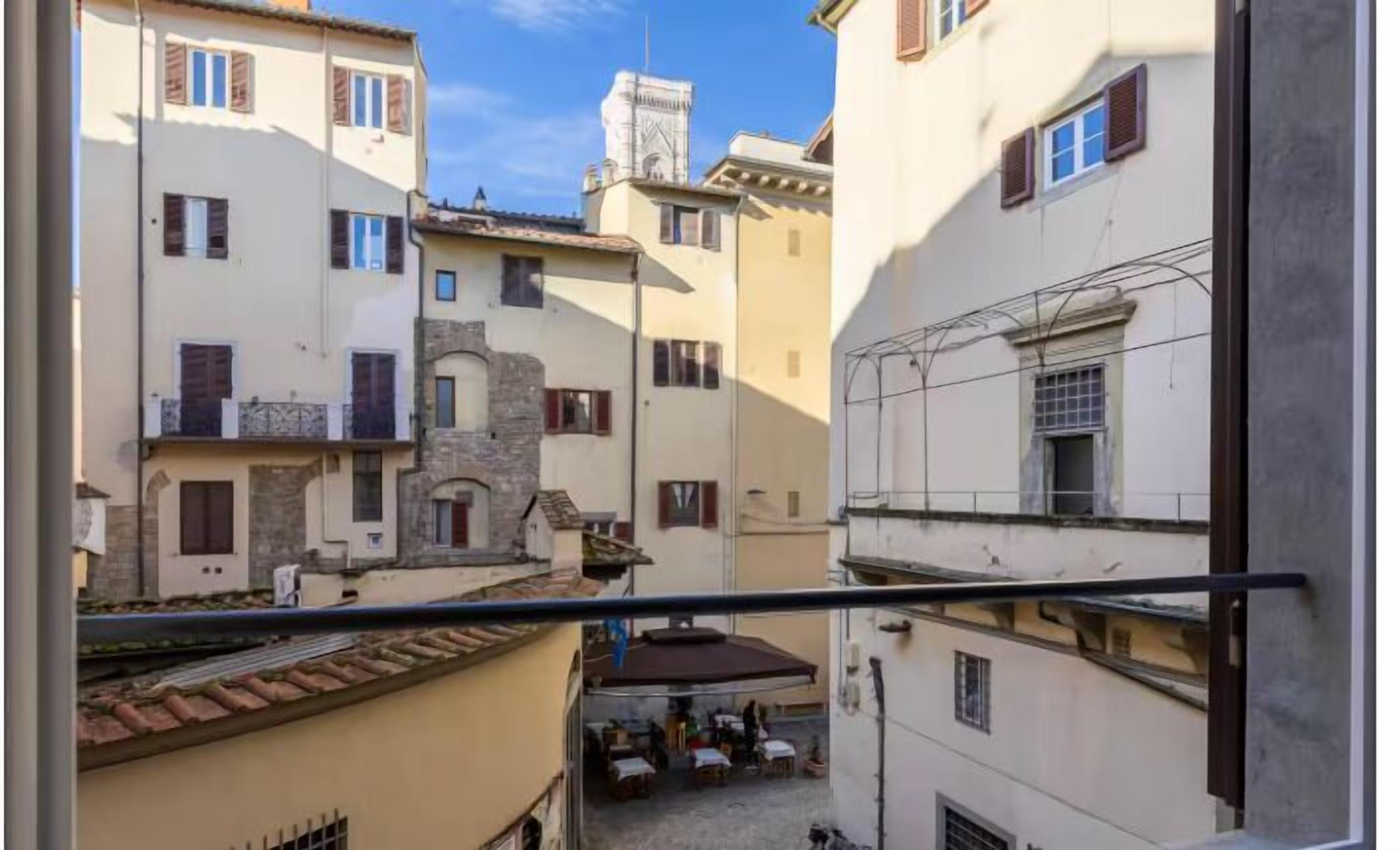 Una calle estrecha flanqueada por edificios, con balcones y ventanas.