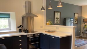 Une cuisine moderne dotée d’un four encastré, d’une hotte en acier inoxydable et de luminaires suspendus.