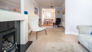 Una sala de estar con chimenea, un sillón blanco, una silla negra y un sofá.