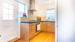 Una cocina con armarios de madera, una estufa y una ventana.