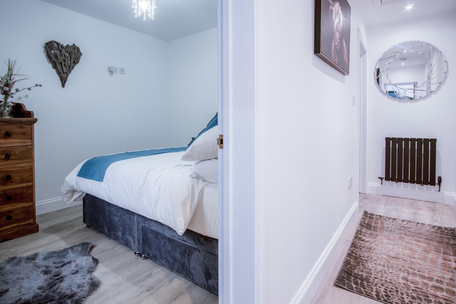 A bedroom with a bed, dresser, and a wall-mounted heater.