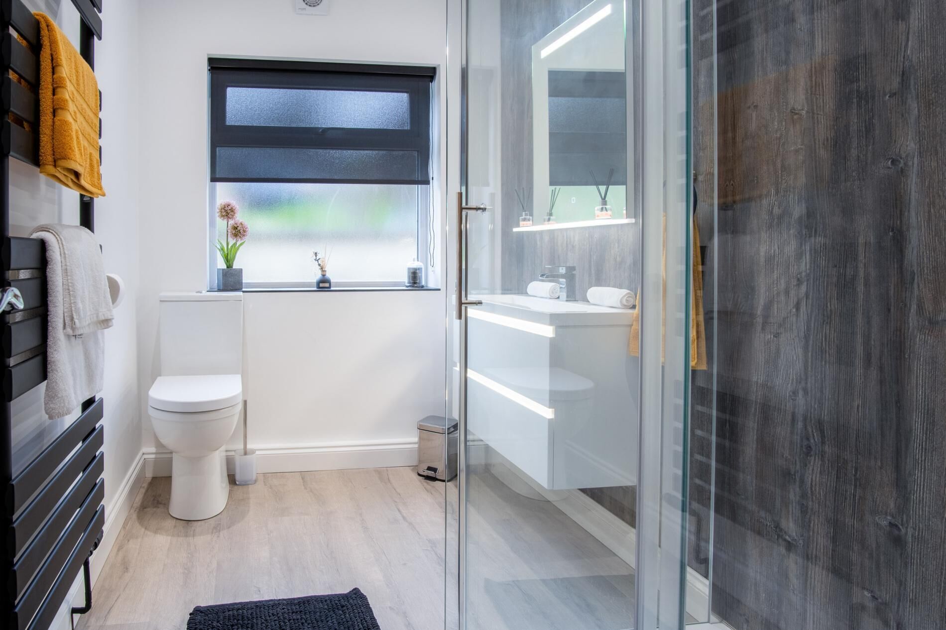 A modern bathroom with a toilet, a window with a view, a shower area, and a sink.