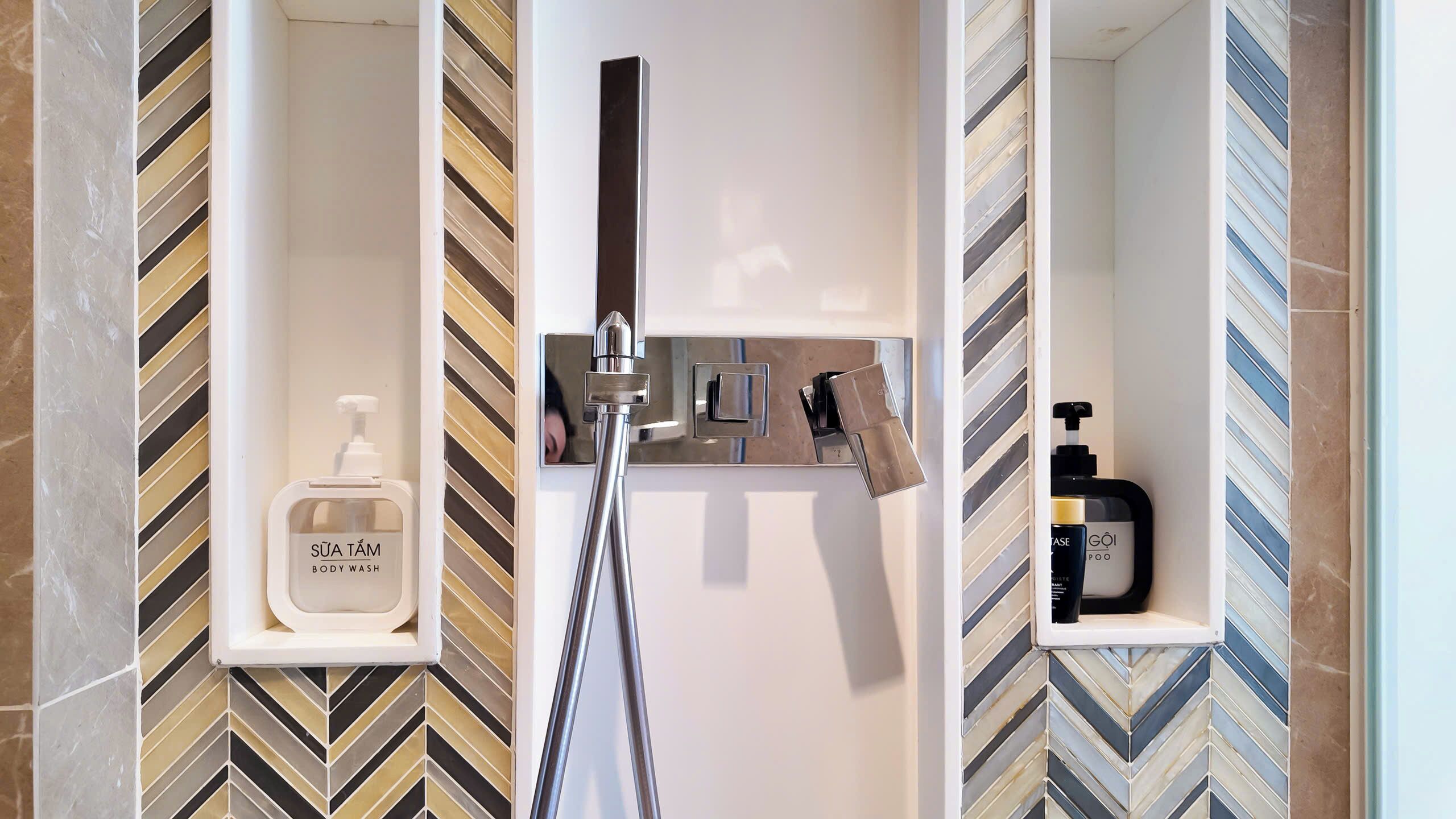 A modern bathroom with a shower, a soap dispenser, and a shampoo bottle.
