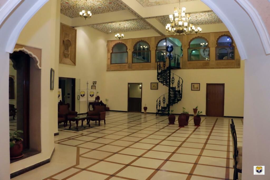 A spacious lobby with a tiled floor, a spiral staircase, and several potted plants.
