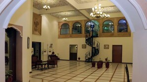 A spacious lobby with a tiled floor, a spiral staircase, and several potted plants. - Deoki Niwas Palace (Jaisalmer)