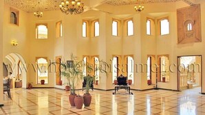 A spacious lobby with a tiled floor, multiple arches, and potted plants. - Deoki Niwas Palace (Jaisalmer)