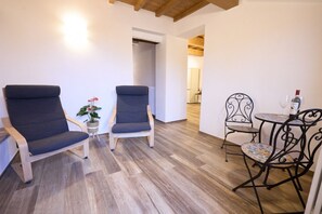 Una habitación con dos sillones tapizados, una mesita con un vaso y una planta en maceta.