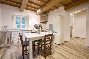 Una cocina con vigas de madera, un refrigerador blanco y una mesa de comedor con sillas.