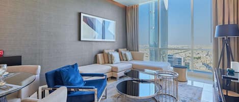A modern living room with a sofa, armchairs, a coffee table, and a large window offering a city view.