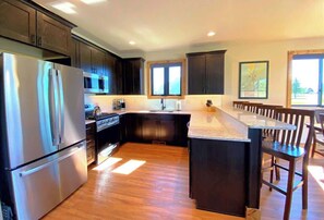 A modern kitchen with dark cabinetry, stainless steel appliances, and a central island. - HuckleBeary Hideaway- Mountain Views- Hot Tub (Red Lodge)