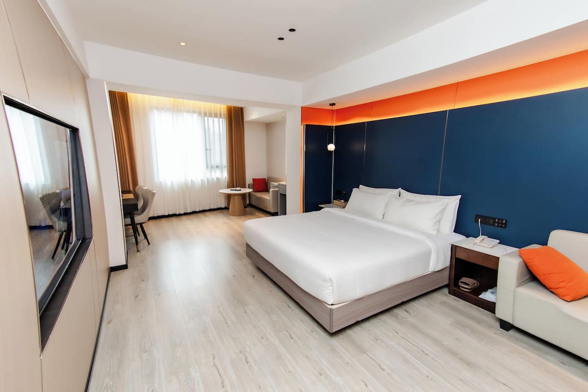 Een moderne hotelkamer met een groot bed, een sofa, een televisie en een bureau.