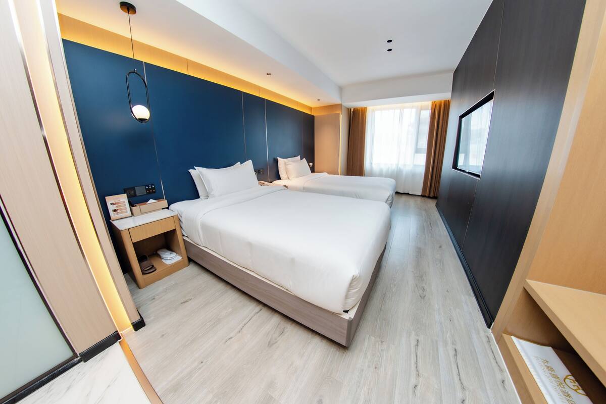 Een moderne hotelkamer met een groot bed, nachtkastjes, een kledingkast en een raam met gordijnen.