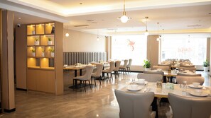 A modern restaurant with a high ceiling, pendant lighting, and a seating area with tables and chairs. - Jiuding Joy Hotel (Kathmandu)
