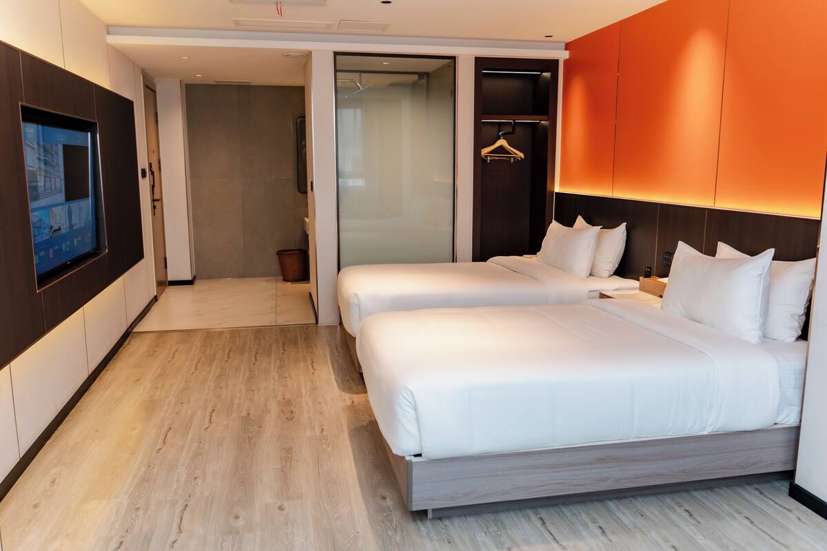 Een moderne hotelkamer met een groot bed, een aan de muur bevestigde televisie en een inloopkast.