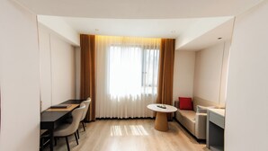 A modern hotel room with a dining table, chairs, a sofa, and a small round table. - Jiuding Joy Hotel (Kathmandu)