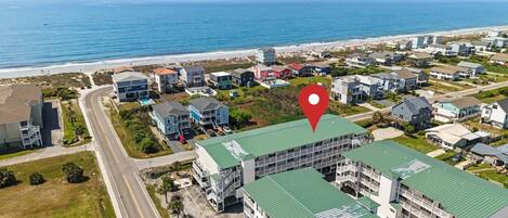 An aerial view of a coastal residential area with a prominent building marked by a red location pin.
