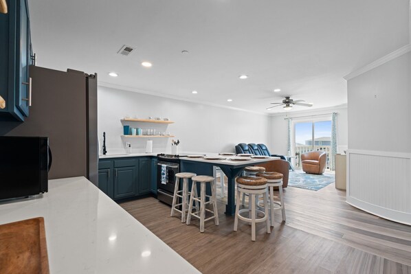 Una cocina moderna con una isla central, taburetes de bar y vistas al exterior.
