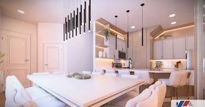 Una cocina moderna con armarios blancos, iluminación colgante y una isla central con asientos.