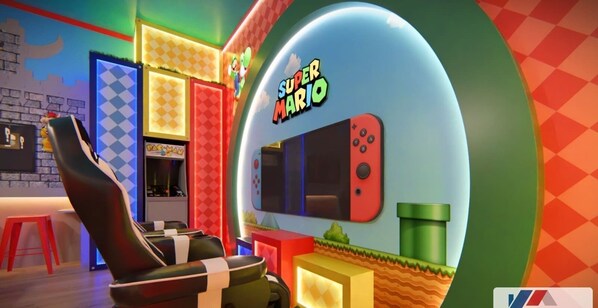 Ein Super-Mario-zimmer mit einer Spielkonsole, einem roten Hocker und einer Wand mit Rautenmuster.