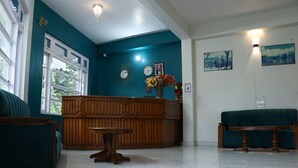 A reception area with a wooden reception desk, a clock, and a vase with flowers.