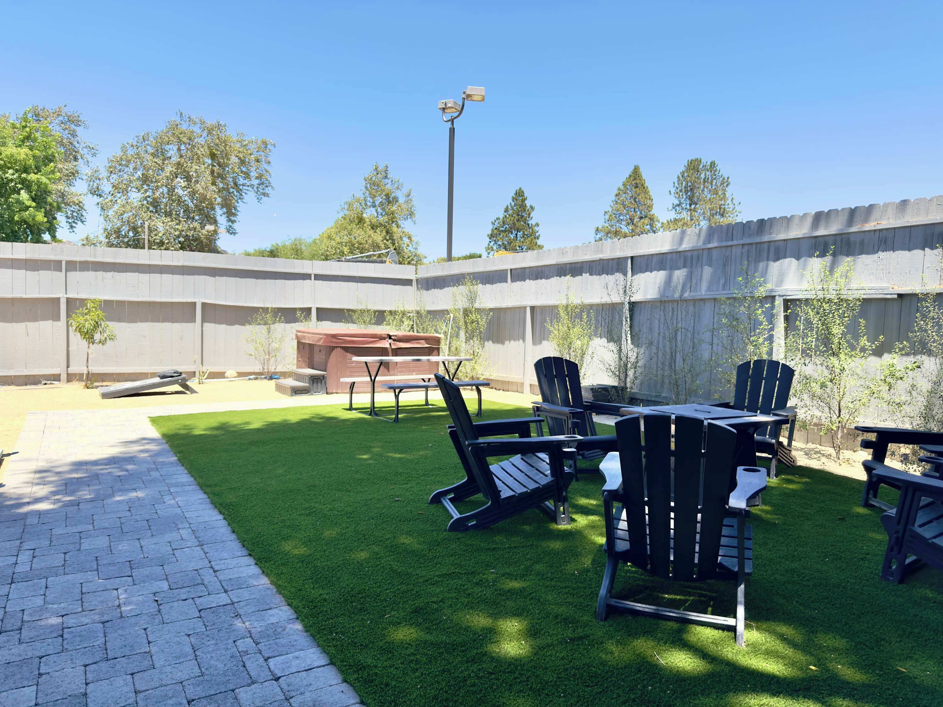 A backyard with a barbecue, outdoor seating, and a paved walkway.