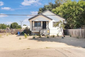 A single-story house with a front porch, a small front yard, and a wooden fence.