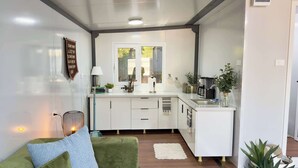 Una cocina moderna con armarios blancos, una cafetera y un ventanal con vistas.