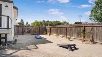 Un jardin à l’arrière de la maison, avec une clôture en bois, un tapis bleu et un petit espace aménagé en jardin.