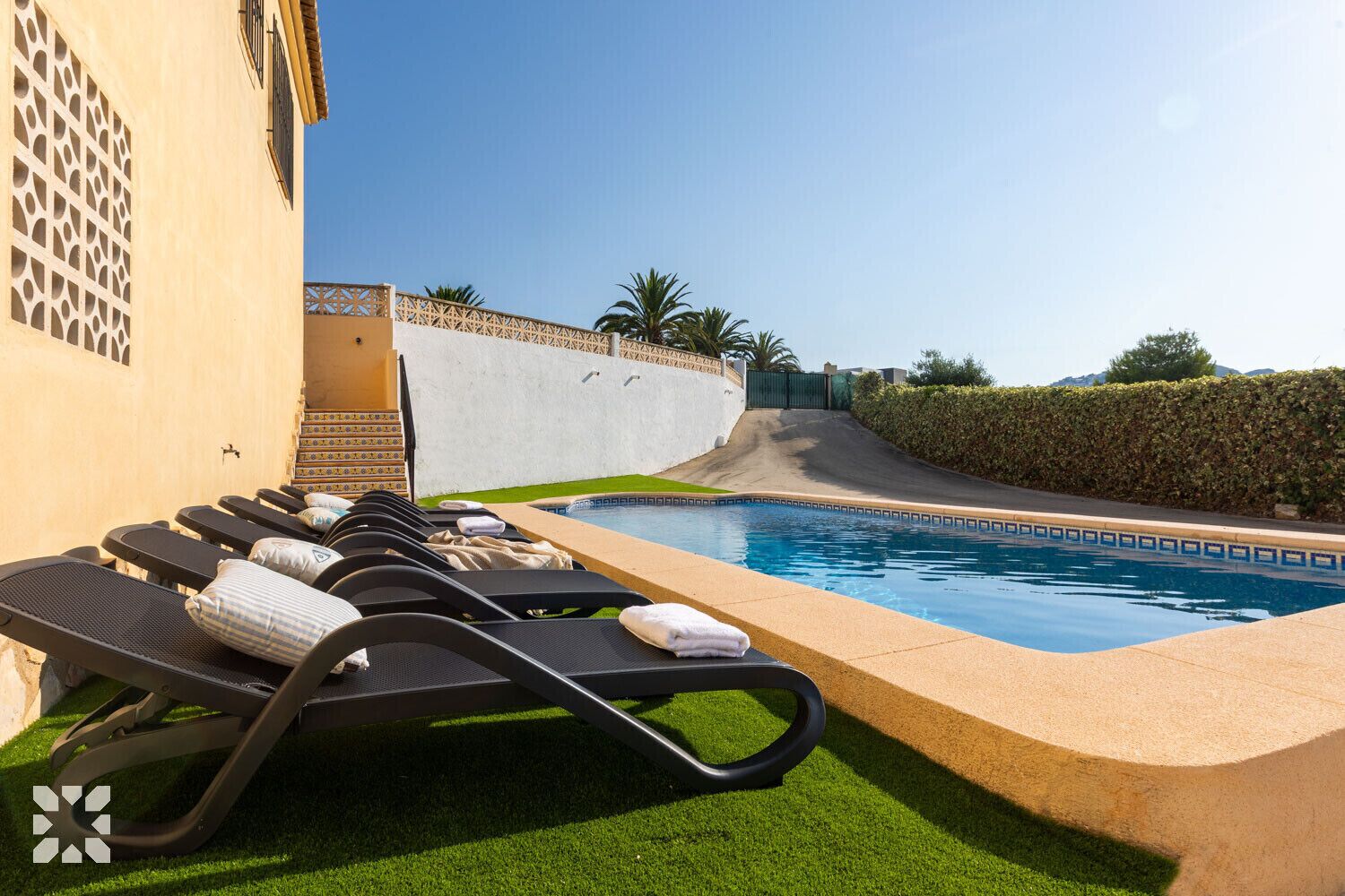 Un área de piscina con sillones de descanso y una piscina pequeña.