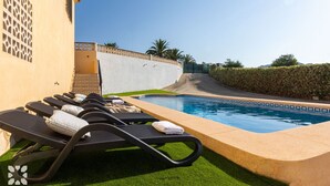 Un área de piscina con sillones de descanso y una piscina pequeña.