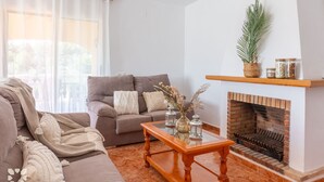 Una sala de estar con chimenea, dos sofás, una mesa de centro y elementos decorativos.