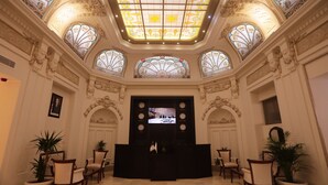 Un vaste hall d’entrée avec un plafond haut, de magnifiques vitraux et un comptoir d’accueil central.