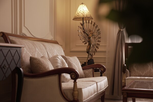 Una sala de estar elegantemente decorada con un sofá clásico, una lámpara decorativa y una mesa de centro de madera.