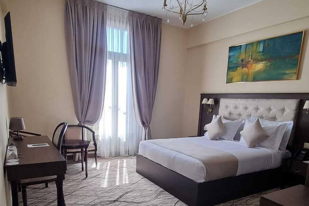 Une chambre d’hôtel avec un lit, un bureau, une chaise, une télévision et un tableau au mur.