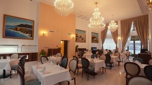 Une salle à manger avec des tables dressées, des lustres et des œuvres d’art accrochées aux murs.