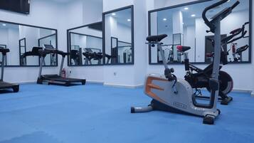 A gym with exercise equipment, large mirrors, and a blue floor.