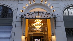 L’entrée du Grand Hôtel, avec sa façade classique, ses balcons richement décorés et son imposant lustre.