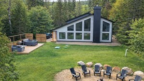 A modern house with a deck, outdoor seating, and a fire pit. - Spa, River, Pool Table | Chalet Ombre & Lumière (Entrelacs)