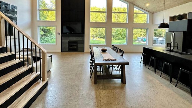 A spacious kitchen with a large dining table, a built-in oven, and a view of the outdoors through large windows. - Spa, River, Pool Table | Chalet Ombre & Lumière (Entrelacs)