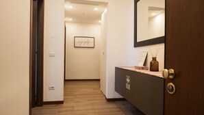 A hallway with a wooden floor, a framed sign on the wall, a mirror, and a cabinet with a lock. - MILANO 71 HOME (Milan)