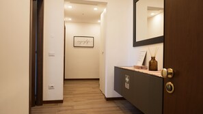 A hallway with a wooden floor, a framed sign on the wall, a mirror, and a cabinet with a lock. - MILANO 71 HOME (Milan)