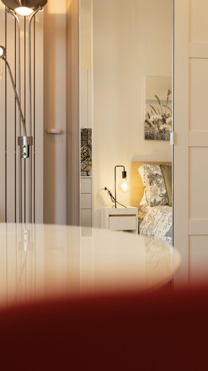 Un dormitorio moderno con cama, lámpara de noche y una obra de arte en la pared.