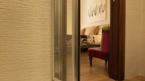 A room with a wooden floor, a red chair, a bed with a floral bedspread, and a wall with a framed picture. - MILANO 71 HOME (Milan)