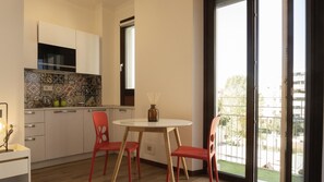 A modern kitchen with white cabinets, a tiled backsplash, and a window overlooking a balcony. - MILANO 71 HOME (Milan)