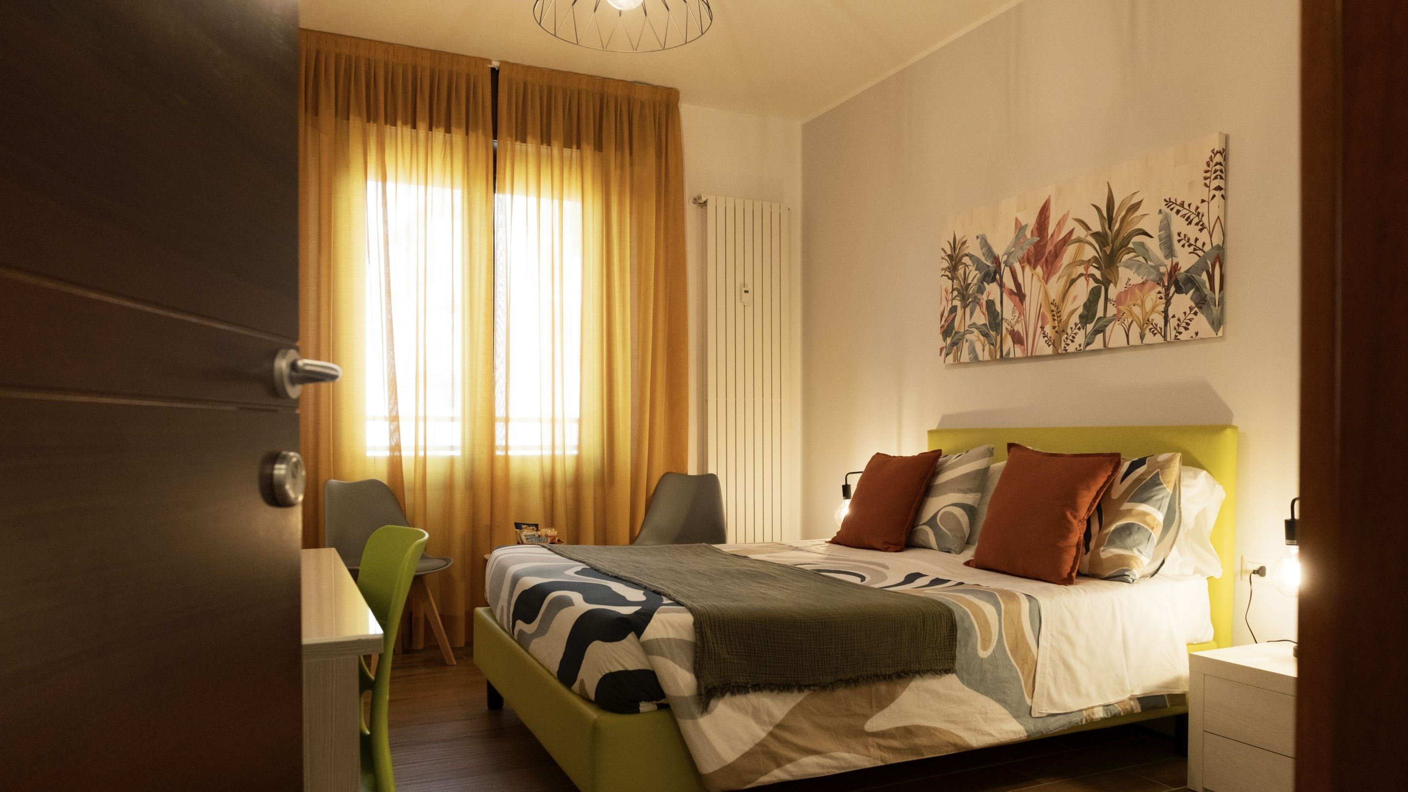 Une chambre à coucher avec un lit, une chaise, un bureau, un radiateur et un tableau accroché au mur.