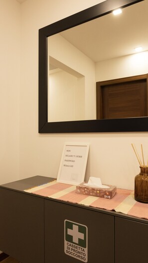 A room with a mirror, a framed sign with WiFi details, a tissue box, and a first aid kit. - MILANO 71 HOME (Milan)